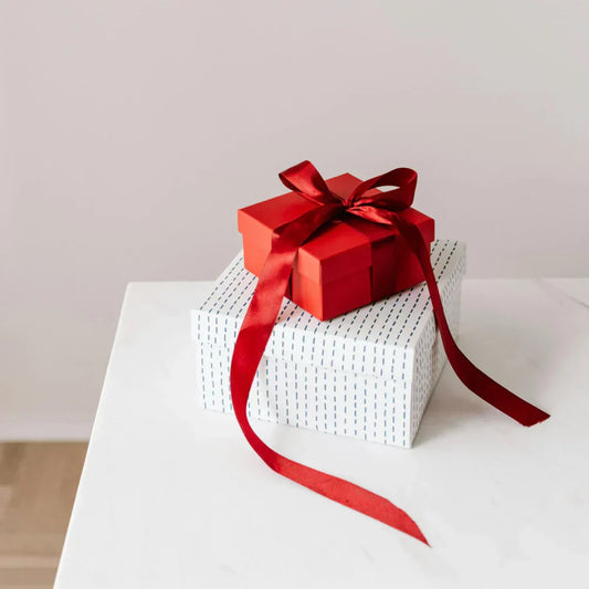 Geschenke auf einem hellen Tisch mit roter Schleife